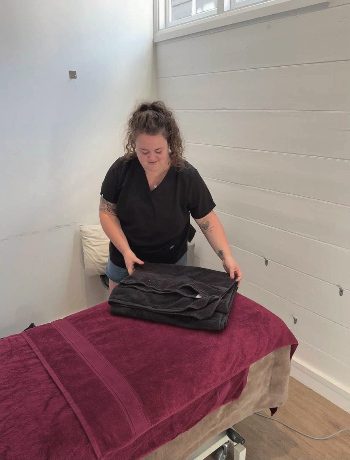 Lois folding warm towels on the massage couch at the West Malling clinic